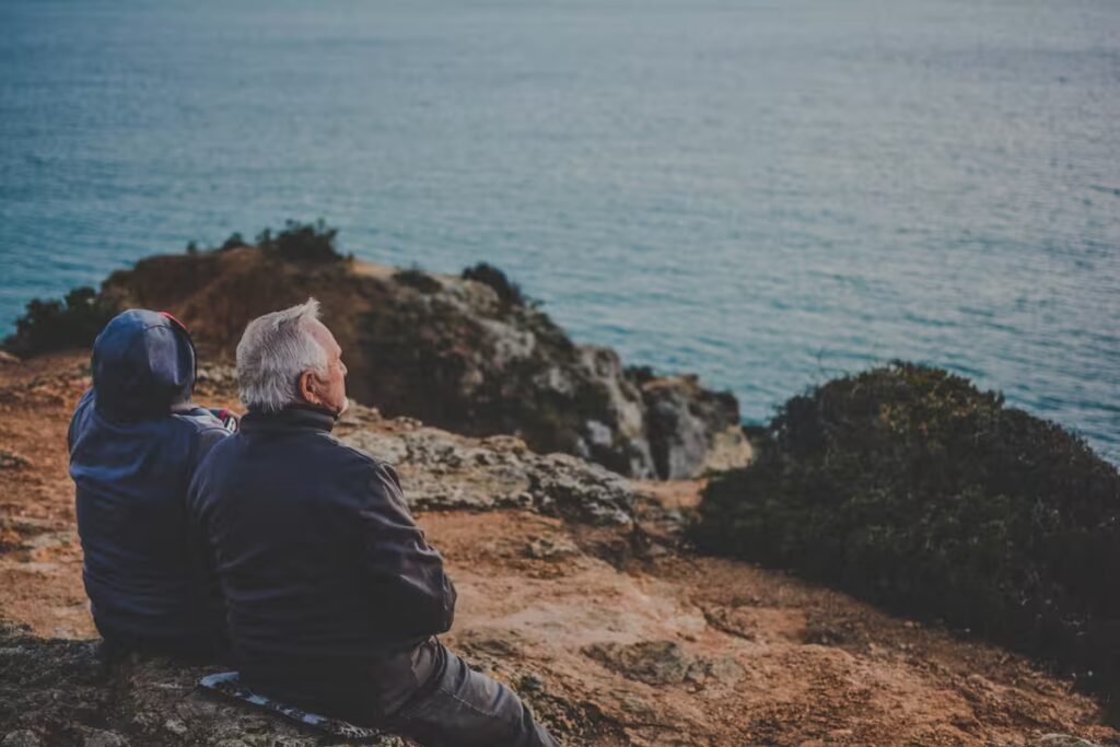 A couple sitting on a cliff, embracing nervous system healing and moving from survival mode to thriving.